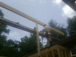 Carpenter setting a ridge beam over a new addition frame — Ice Dam Removal by Roofing Brothers in Coalfield
