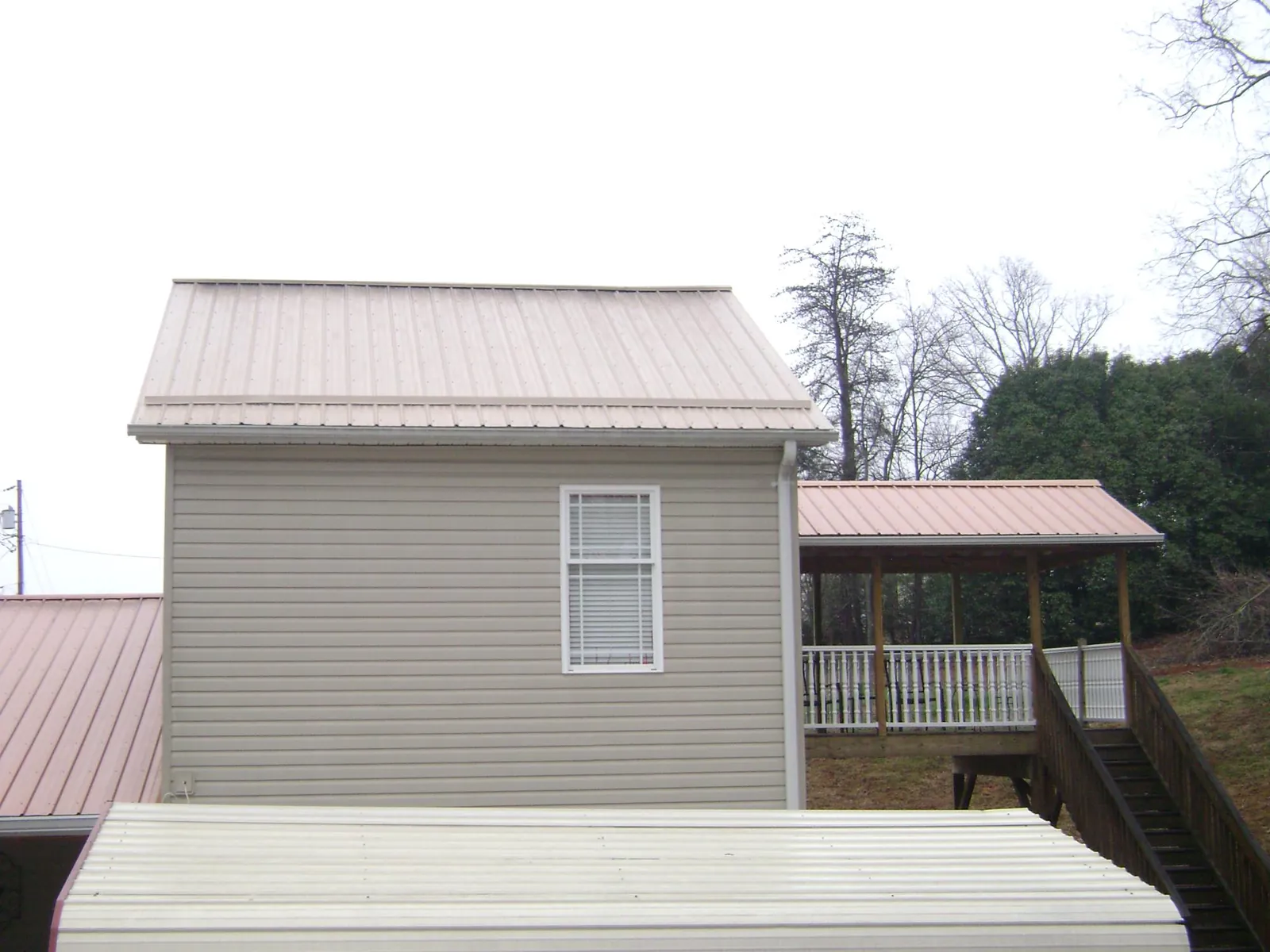 Tan metal roofs on a two story addition and attached porch, from a Roof Replacement job in Coalfield