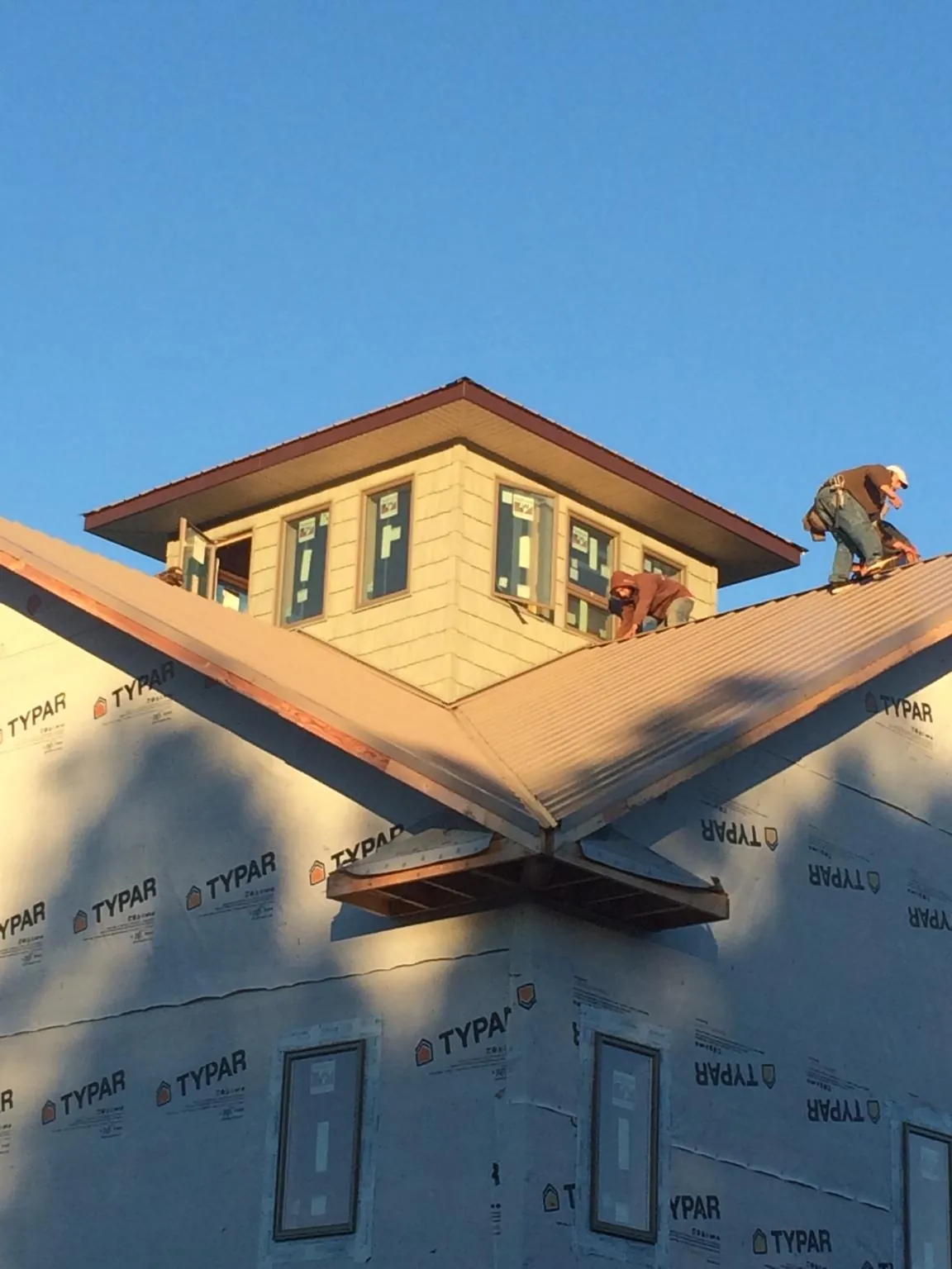 Roofers working around a rooftop cupola on a new metal roof at sunset — Roof Waterproofing in Coalfield by Roofing Brothers